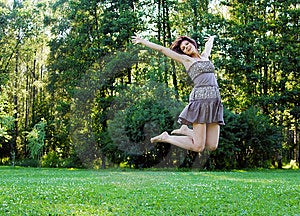 Souriant belle fille heureuse de sauter dans un parc en été.