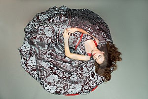 Extravagante junge Dame auf Farbe Kleid Verlegung auf dem Boden mit geschlossenen Augen getrennt.