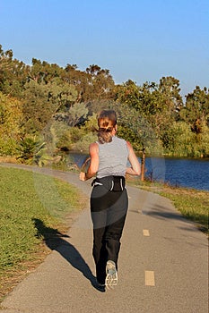 Donna jogging lungo un fiume al tramonto.