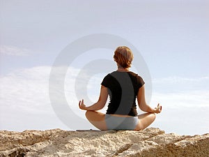 Žena v černém meditovat na skále.