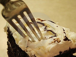 Einen großen Keil von Schokolade Kuchen mit weißem Zuckerguss und weißer Schokolade Späne auf der Oberseite mit einer Gabel zu Graben in für einen Biss.