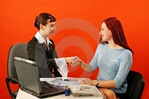 Due giovani, donna si stringono la mano in ambiente di lavoro.