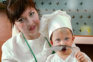 Sonriente madre a su pequeno un hijo en Cocinar traje sobre el La cocina.