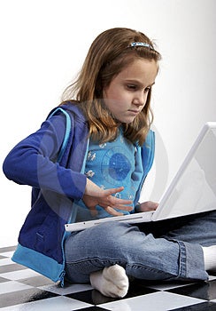 Grundschule Alter Mädchen arbeiten auf einem weißen laptop-computer beim sitzen crosslegged auf dem Boden.