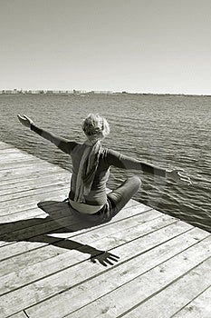 Šťastie slobody, zdravý životný štýl, voľný čas a relaxovať v blízkosti vody, predmestská zvyšok, žena dosiahne na slnečné svetlo a dýchať sviežosťou prírody, ona sedí na móle s výhľadom na modré vody.