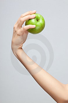 Žena Kaukazský ruke drží celé zelené jablko na sivá studio pozadí.