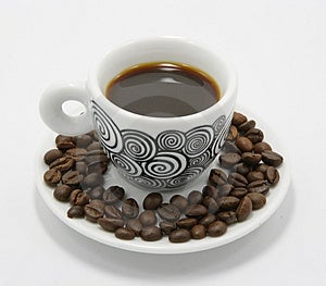 Tasse Kaffee mit Kaffeebohnen auf weißem hintergrund.