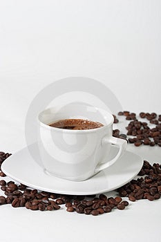 Bianco tazza di caffè su un piatto e chicchi di caffè.