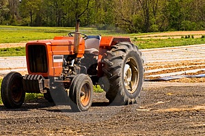 Pohľad na červený farmy traktora v blízkosti novo vysadené oblasti skoro na jar.