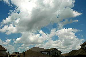 Mraky Letní oblohou visí nízko nad domy v okolí.