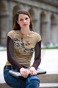 Krásná mladá žena s notebookem sedí venku.
