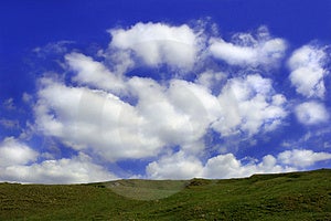 Grasbewachsenen Hügel mit einem blauen Himmel und geschwollene weißen Wolken.