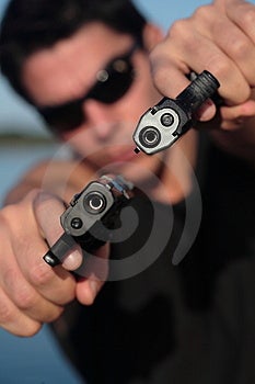 Un uomo in possesso di una pistola e puntandola verso la telecamera.