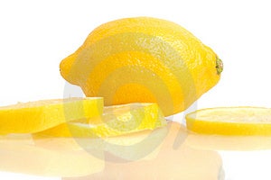 Un limone e fette di limone riflettendo in bianco.