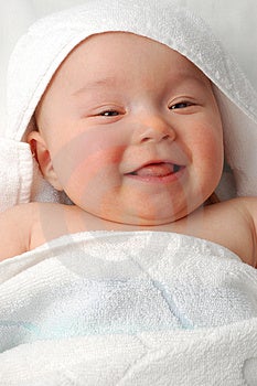 Dolce bambino sotto l'asciugamano su sfondo bianco.