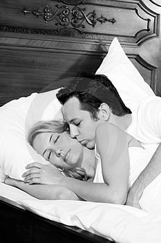 Atractivo joven hombre es un besar su novia, mientras una mujer es un durmiendo.