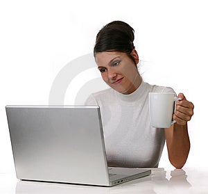 Mladá žena sa pozerá na jej prenosný počítač a nápoje jej kávu na Bielom Extrahovateľné Pozadí.