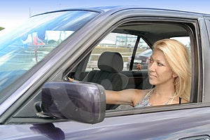 Una ragazza bionda alla guida di un auto.