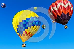 Barevné horkovzdušné balóny proti modré obloze.