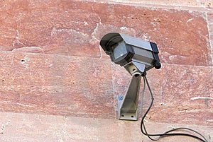 Telecamera di sicurezza montata su rosa muro di pietra.
