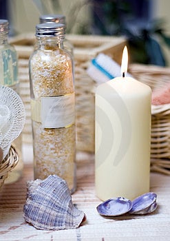 Beige spa-Zusammensetzung, eine Kerze, einige Muscheln, Kosmetik-Flaschen.