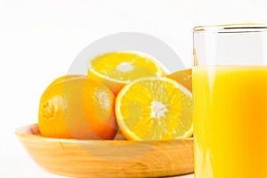 Due metà di arancia in una ciotola di legno con uncut arancia e un bicchiere di succo d'arancia in primo piano.