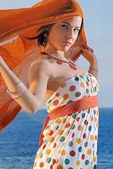 Módní model drží oragne látky proti oceánu pozadí.