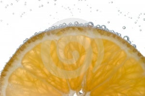 Rebanada de limón retroiluminado burbujas contra blanco.