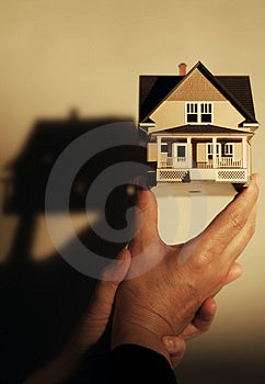 Lidské ruce drží model domu, mělké DOF.