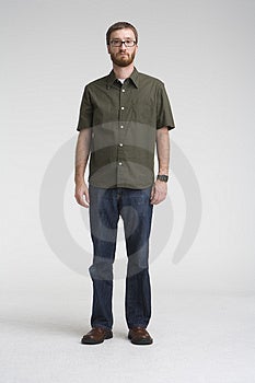 Voller Länge Bild eines Mannes mit BART, trägt ein grünes shirt und jeans steht in einer grauen Foto-studio.
