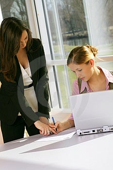 Úspěšné podnikání žena a její sekretářka se dokument na stůl s notebookem.