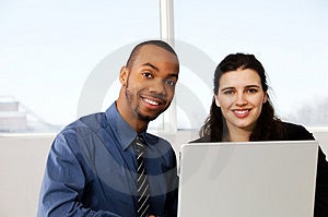 Due colleghi di lavoro con un grigio computer portatile.