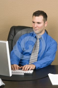 Administratívny pracovník hlboko zapojení do web chatovanie vyzerá na monitore vážne, sa sústredil na písanie.