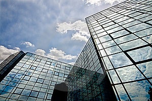Riflettendo edificio per uffici con un bel cielo nuvoloso.