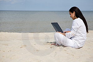 Atraktivní bruneta žena s laptopem na pláži.