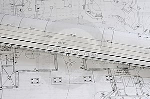 Un bianco frizzante blueprint arrotolato sulla parte superiore di un piano di attività della fondazione.
