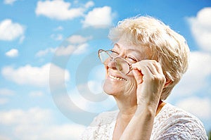 Retrato sonriente más viejo una mujer anteojos contra el cielo.
