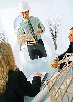 Šťastný kaukazský zhotoviteľ ukazuje domu model dvoch podnikateľka.