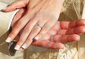 Dve ruky ženatý koniarov s snubné prstene a svadobné šaty.