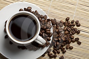 Blanco taza de café a granos de café a través de bambú.