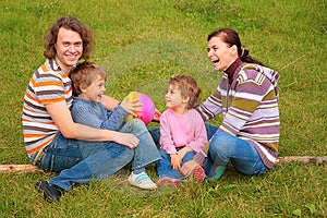 Rodina štyri sedí na zelenej tráve.