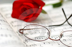 Zblízka hudby list, okuliare, a rose.