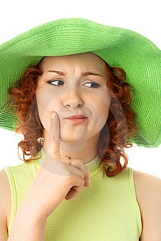 Riflessivo giovane donna con i capelli rossi che indossa un verde estate cappello.