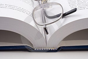 Close-up von einem offenen Buch mit Brille.