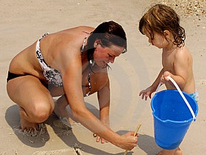 Mutter und Kleinkind spielen im sand am Strand.