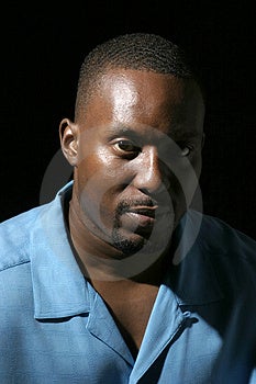 Low key ritratto headshot su sfondo nero di un bel Afro-Americano di sesso maschile con un'espressione seria.